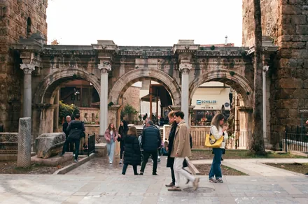 Hadrians port i Antalya med tre marmorbuer og folk som spaserer forbi
