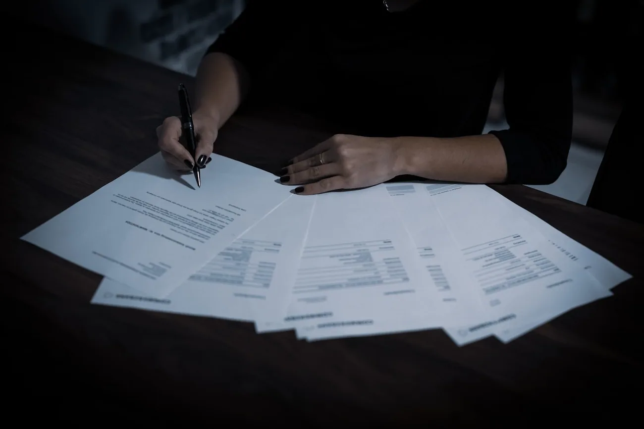 En person går gjennom papirer og skjemaer ved skrivebordet