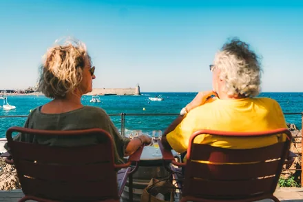 To eldre mennesker sitter og ser utover det blå havet