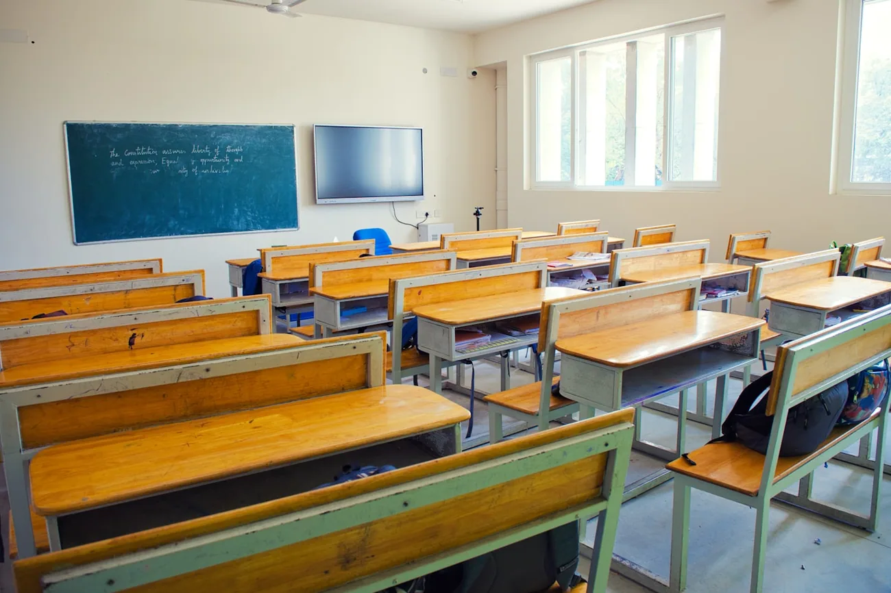 Klasserom med trepulter og tavle før skoledagen begynner