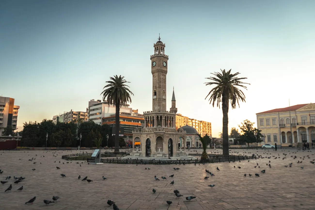 Klokketårnet på Konak-plassen i İzmir med palmer og duer