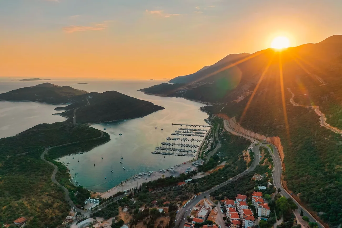 Solnedgang over Kaş med havnebukt, halvøy og hvite hus i skråningen