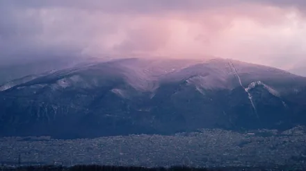 Snøkledde Uludağ hever seg over husene i Bursa i rosa kveldslys