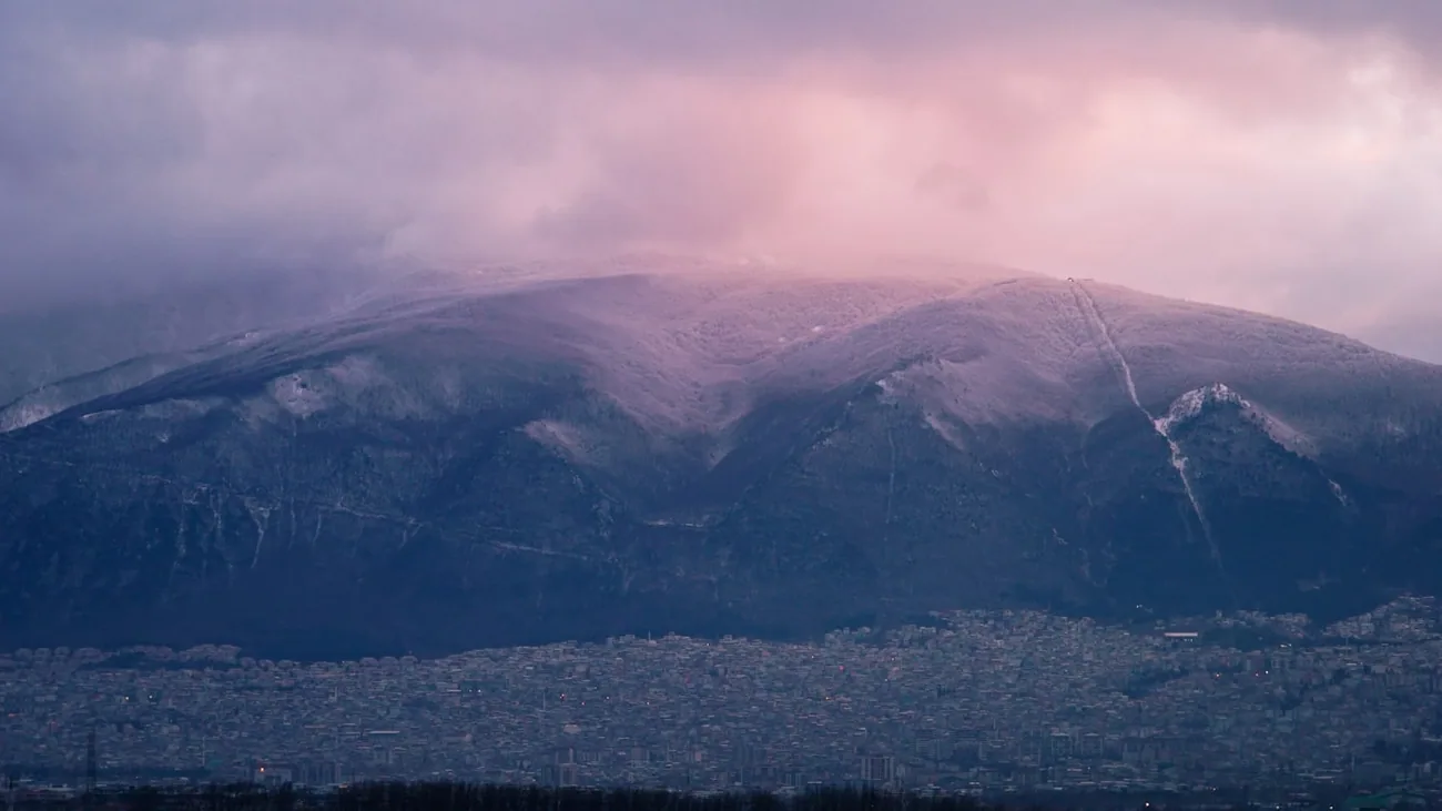 Snøkledde Uludağ hever seg over husene i Bursa i rosa kveldslys