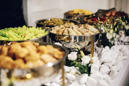 Varmebeholdere med salat og varmretter på en hotellbuffet
