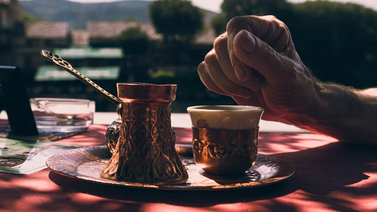 Tyrkisk kaffe i liten kopp med cezve i kobber på et brett