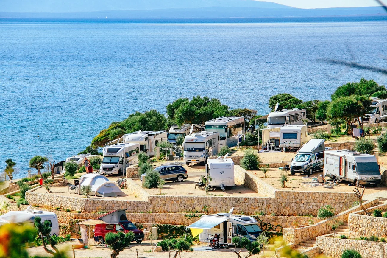 Bobiler parkert på steinterrasser på en campingplass rett ved Middelhavet