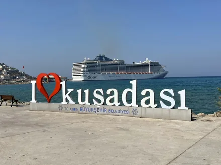 Et cruiseskip på reden utenfor Kuşadası, med byens skilt på kaia i forgrunnen