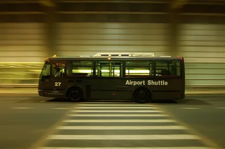 Flyplassbuss i fart på vei forbi terminalen i skumringen