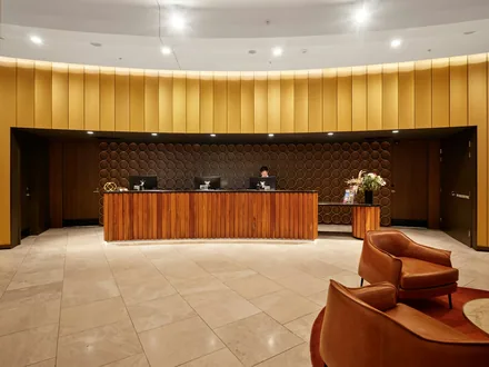 Resepsjonsdisk i en hotellobby med lyse møbler og ansatte bak disken