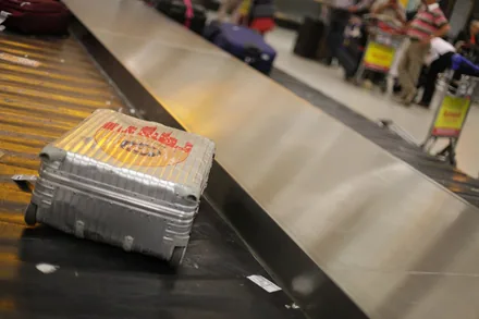 En sølvfarget koffert kommer ut på bagasjebåndet i ankomsthallen på flyplassen