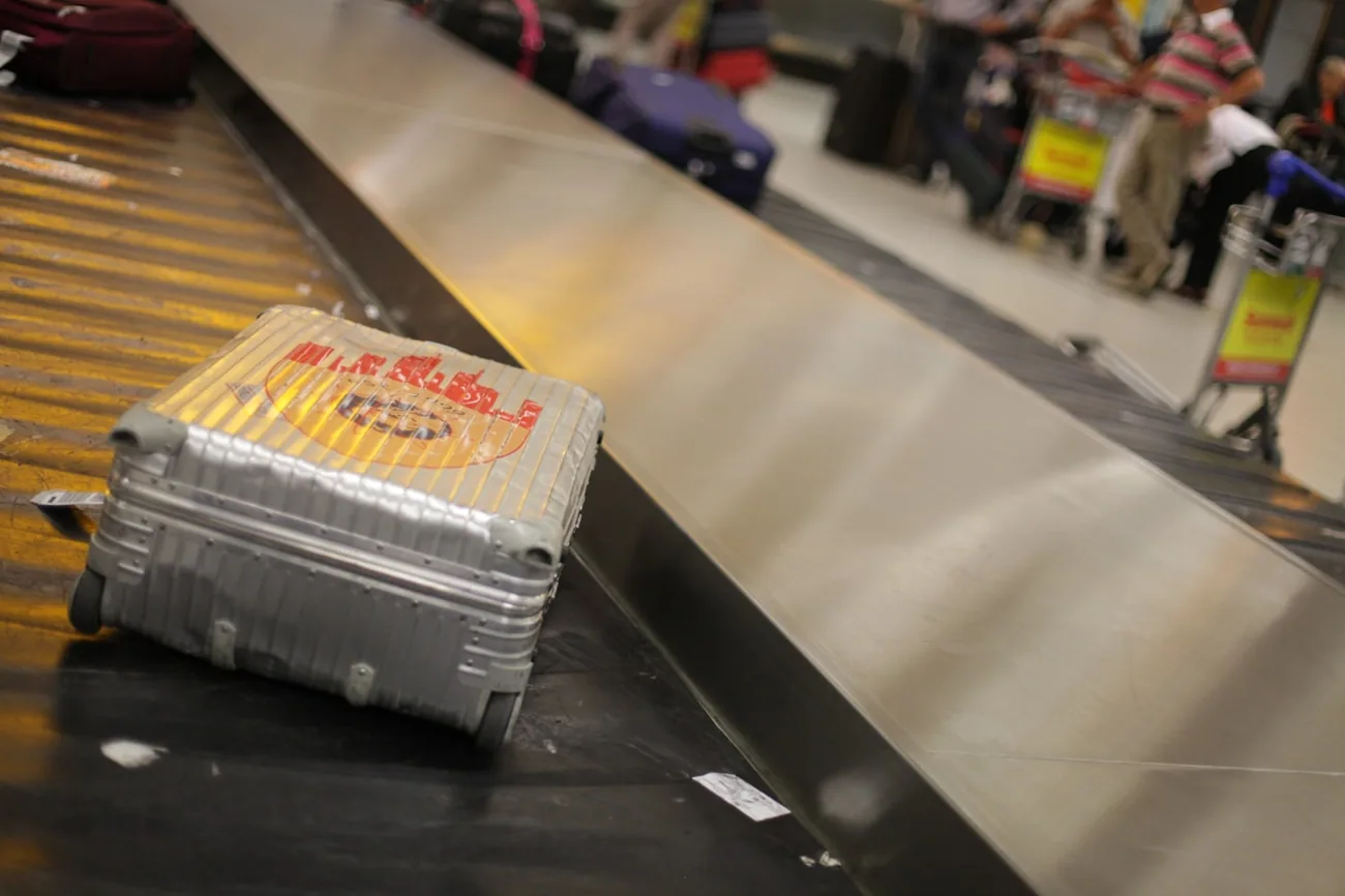 En sølvfarget koffert kommer ut på bagasjebåndet i ankomsthallen på flyplassen