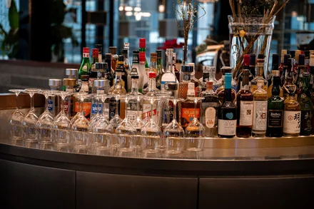 Tett rekke med spritflasker bak en buet bardisk på et utested