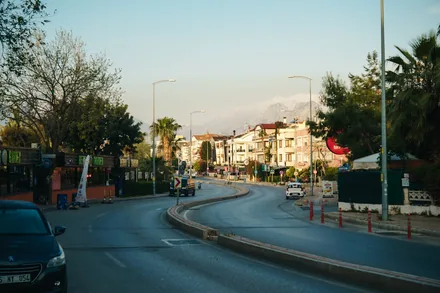 En rolig hovedgate i Antalya med palmer, biler og snødekte fjell i det fjerne