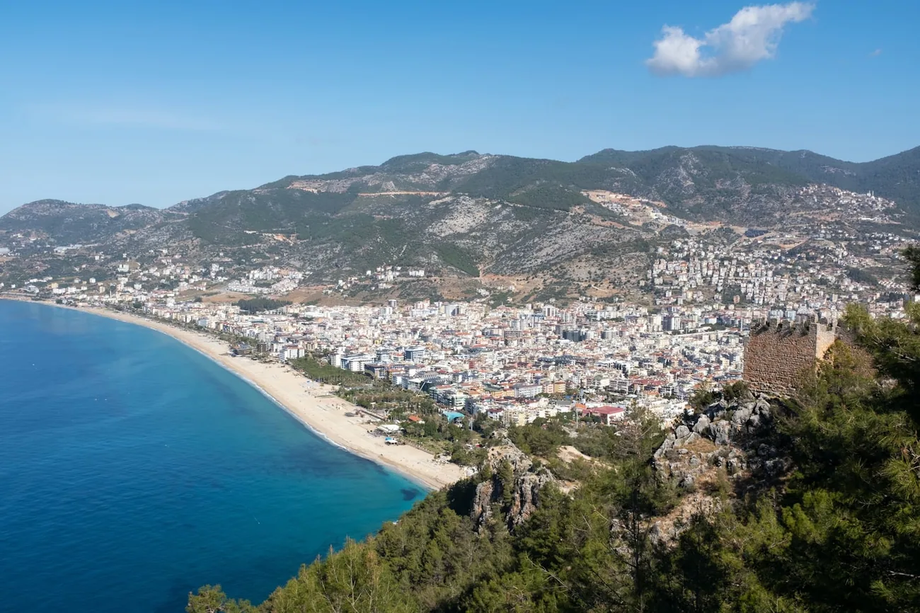 Utsikt fra borgåsen over Kleopatra-stranden i Alanya, med høyblokker og fjell bakenfor