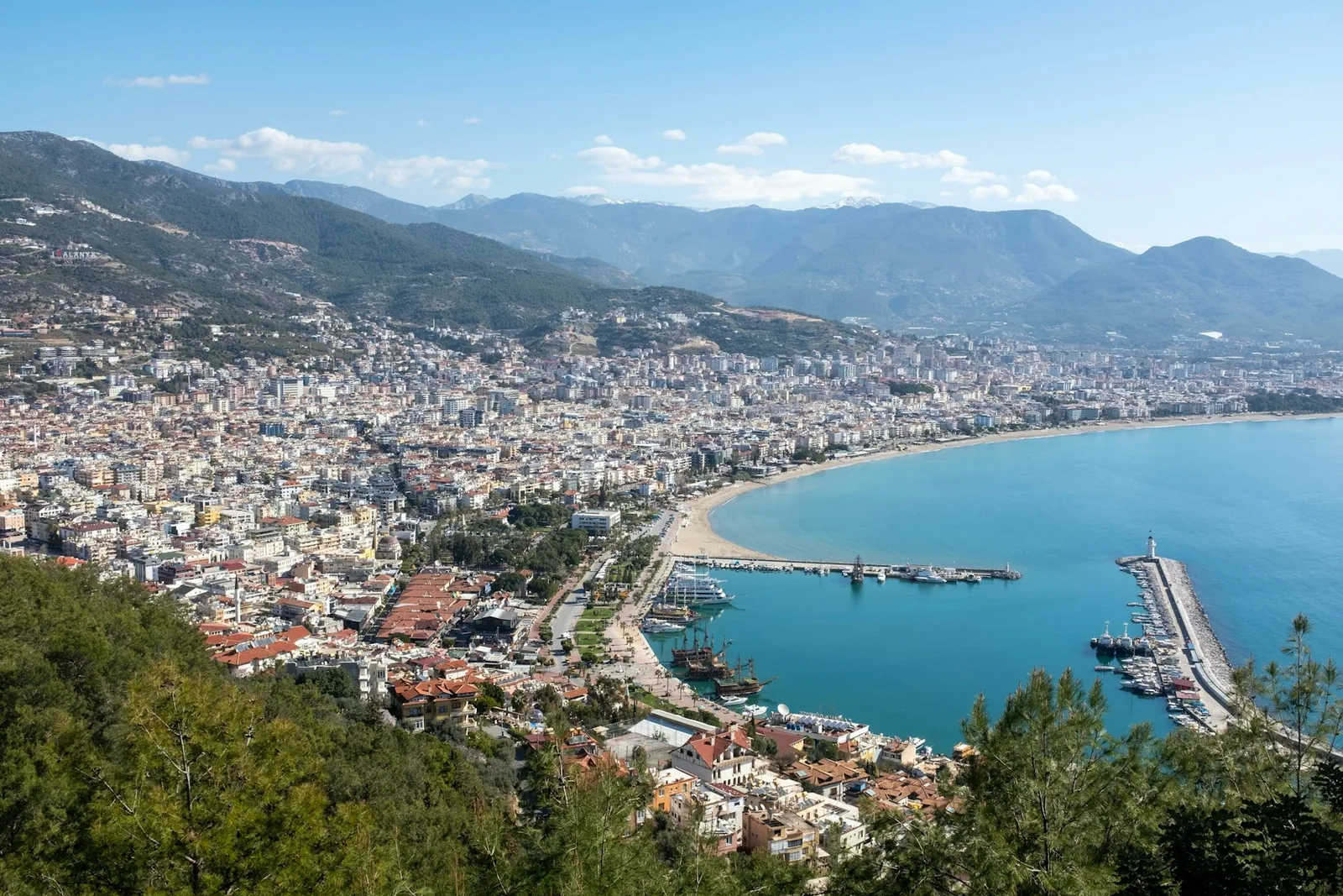 Boligblokker langs bukta i Alanya med fjellene bak