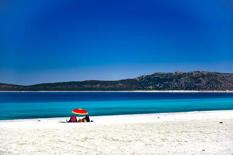Hvit strandbredd og turkist vann ved Salda med en rød parasoll