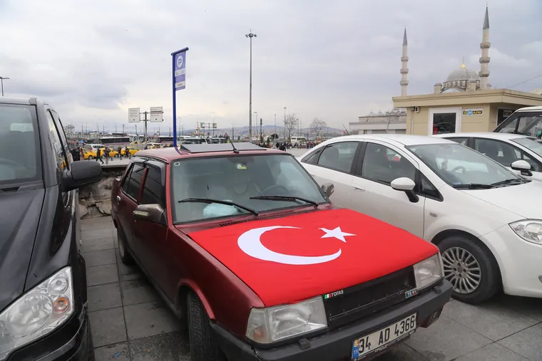Biler parkert tett i en gate i Istanbul, med minareter bak